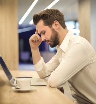 man with hand on temple looking at laptop